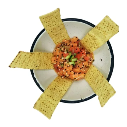 Una porción de cubos marinados color salmón con jitomate, servida con tiras grandes de totopo.