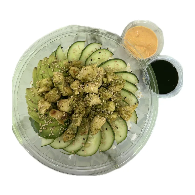 Trozos de pollo bañados en pesto verde sobre arroz, con pepino, aguacate y ajonjolí, empacado para llevar con salsas al lado.