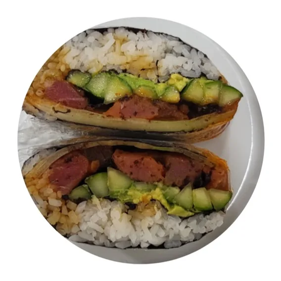 Un rollo de arroz envuelto en alga nori, cortado a la mitad, relleno de pescado en cubos con salsa picante, aguacate y pepino.